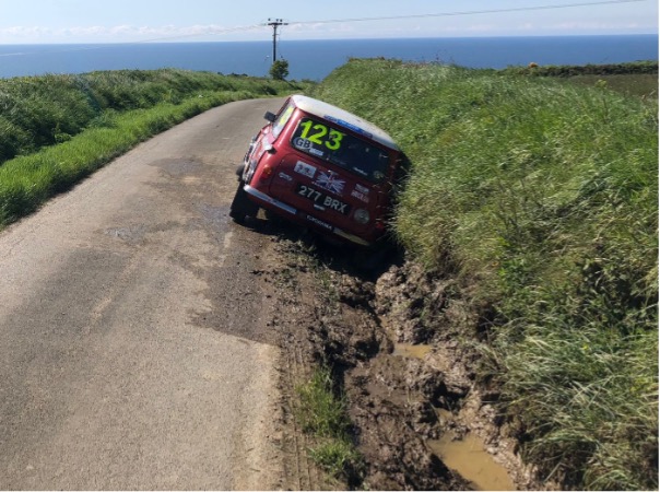 Car beached on sump guard in very muddy ditch.